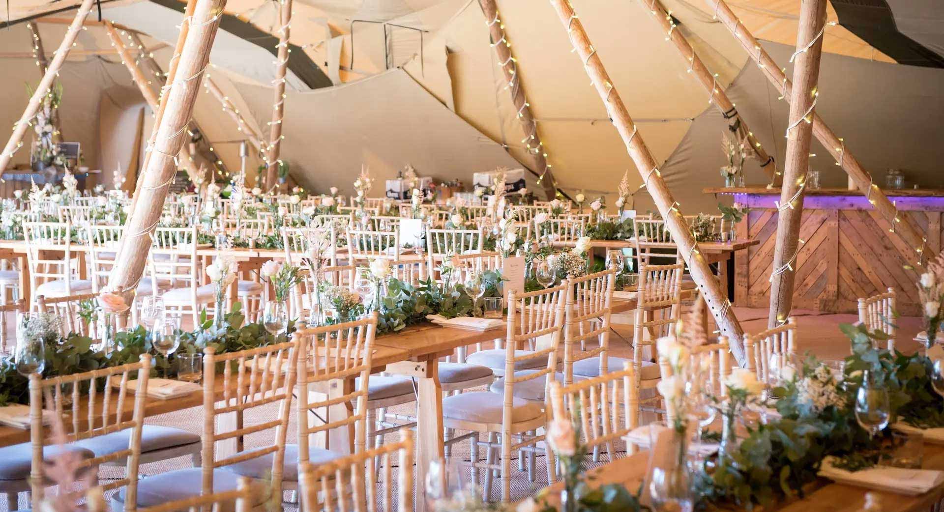 Long tables inside tipi decorated with greenery